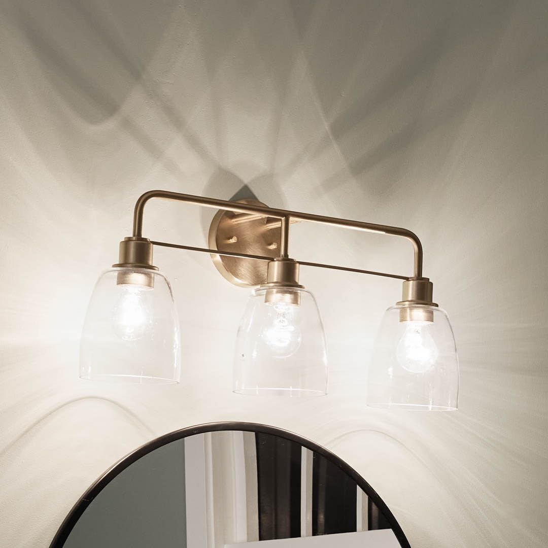 Kichler Meller 24.25' 3-Light Bathroom Vanity Light Fixture with Clear Glass Shades in Champagne Bronze for Mirror or Powder Room (24.25' W x 11.25' H x 7' D) 55102CPZ